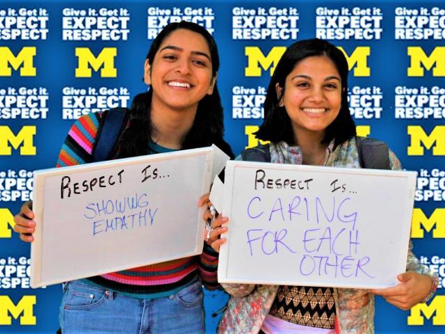 Two students holding up whiteboards saying what respect means to them